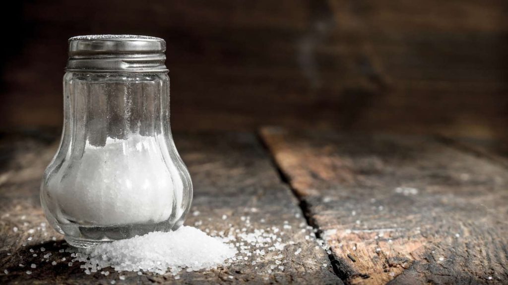 salero con sal derramada en una mesa de madera vieja
